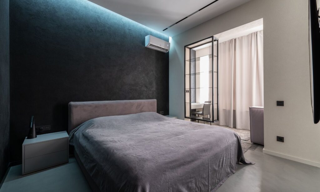 Ductless mini split indoor unit mounted high on the wall of a modern bedroom