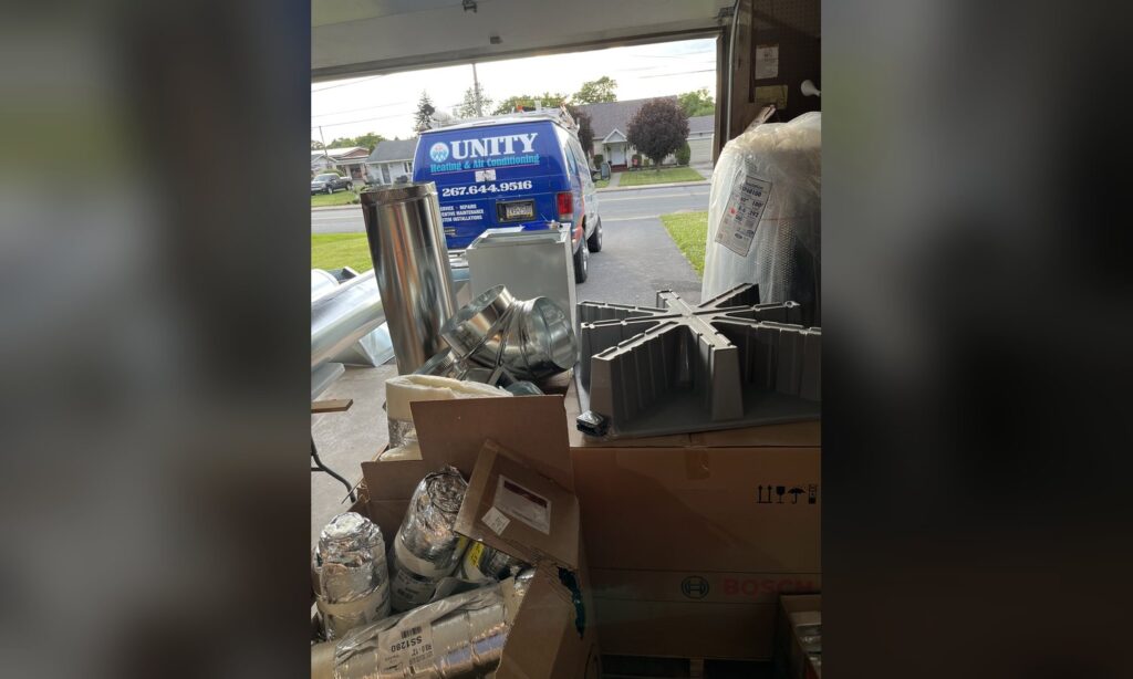 Unity Heating & Air Conditioning service van with sheet metal ductwork fittings staged in a garage before a new installation